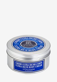 Rund silverfärgad burk med en blå etikett, märkt 'Ultra Rich Body Cream', med vit text och en ikon av sheasmör, 200 ML kapacitet.
