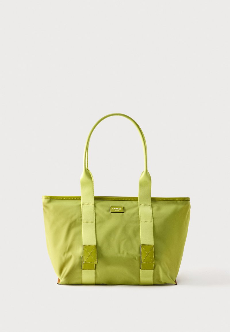 Sac fourre-tout vert avec deux longues anses, base rectangulaire et petite étiquette de logo à l'avant portant l'inscription "Lancel Paris".