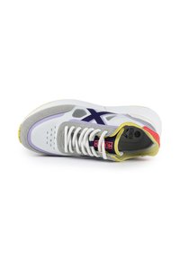 Baskets de sport blanches avec des accents gris, violet et jaune. Dotées d'une tige en maille, de lacets ronds et d'une semelle texturée avec un logo au talon.
