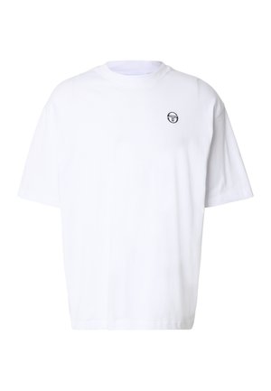 T-shirt bianca oversize a manica corta con piccolo logo circolare nero sul petto in alto a sinistra, design semplice, scollo rotondo.