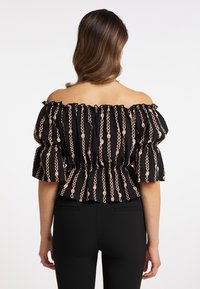 Černá off-shoulder blůza s řaseným výstřihem, balónovými rukávy a vzorem řetězce v růžových a zlatých tónech. Tvarovaný peplum pas.