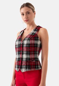 Rood, zwart en wit geruit mouwloos vest met een V-hals ontwerp, voorzien van vijf zwarte knopen en een getailleerde pasvorm.