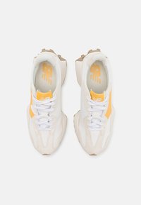 Weiße und beige Sneakers mit gelben Akzenten. Zu den Eigenschaften gehören Schnürverschluss, gepolsterte Kragen, strukturierte Materialien und ein klobiges Sohlen-Design.