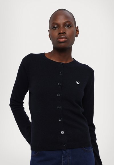 Svart strikket cardigan med rund hals, frontlukking med knapper, og et lite brodert mønster på venstre bryst. Glatt tekstur.