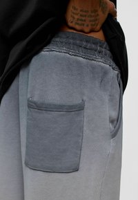 Grijze joggerbroek met een zijzak, elastische tailleband met geplooide textuur en een gladde katoenmixstof.