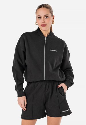 Svart kortad sweatshirt med dragkedja och ribbade muddar, tillsammans med svarta shorts med elastisk midja, med en vit logotyp som accent.