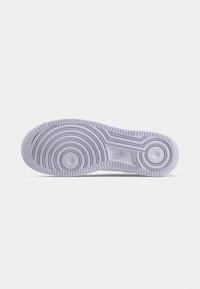 Sole of a white Nike sneaker with circular and linear tread patterns on a plain white background.