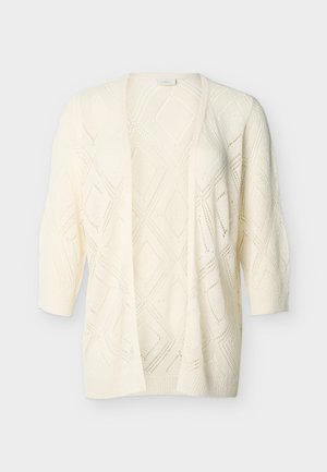 Πλεκτή ζακέτα εκρού με ανοιχτό εμπρός μέρος, μοτίβο διαμαντιών και μανίκια τριών τετάρτων, σε απλό φόντο.