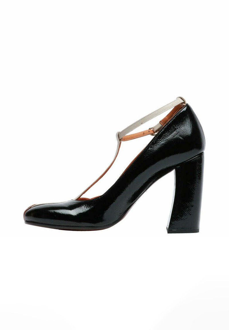 Scarpa con tacco alto in pelle verniciata nera con punta appuntita, tacco largo e robusto e cinturino incrociato sulla parte anteriore, con un accento color cuoio.