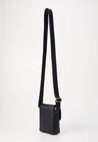 Borsa a tracolla nera con un motivo testurizzato, forma rettangolare, tracolla regolabile e dettagli in metallo. Materiale in pelle liscia.