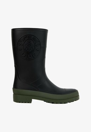 Botte de pluie en caoutchouc noir avec semelle texturée verte et logo Dior circulaire embossé sur la tige supérieure.