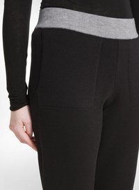 Zwarte legging met een grijze tailleband, gemaakt van zacht materiaal, voorzien van twee zijzakken en een aansluitend ontwerp.