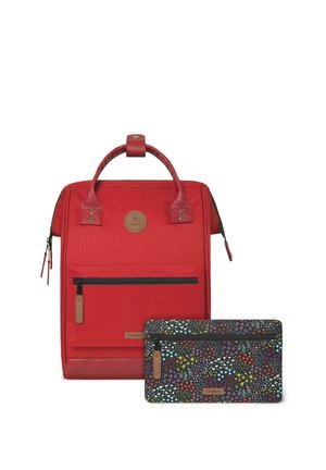 Roter Polyester-Rucksack mit strukturierter Oberfläche, obenem Tragegriff, Vordertasche mit Reißverschluss und einer abnehmbaren schwarzen Tasche mit einem bunten Blumenmuster.