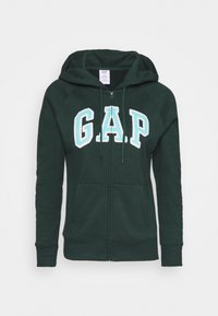 Felpa verde con zip, dotata di cappuccio, grande logo ricamato "G.A.P." in azzurro e tasche frontali. Materiale morbido con polsini a coste.