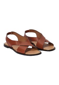 Sandales en cuir marron avec un design à brides croisées, talon ouvert et semelle plate. Semelle intérieure texturée avec des accents beige et un contour minimaliste noir.