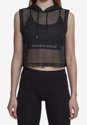 Ærmeløs sort netcropped hættetrøje med snøre over en sort sports-bh, kombineret med højtaljede sorte leggings.