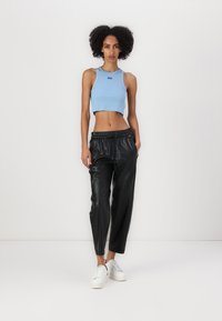 Lichtblauw cropped tanktop, zwarte leren joggers met elastische tailleband, en witte sneakers met dikke zolen.
