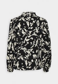 Svart blus med en löst passform, långa ärmar och ett vitt abstrakt mönster. Mjuk tyg med en rynkad halsringning och manschetterade ärmar.