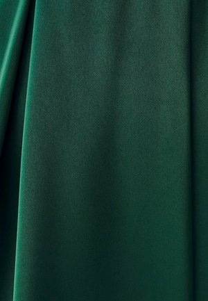 Tmavozelená látka s jemnými záhybmi a hladkým, mierne textúrovaným povrchom zblízka.