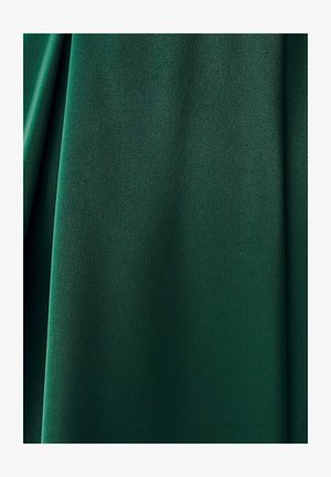 Tmavozelená látka s jemnými záhybmi a hladkým, mierne textúrovaným povrchom zblízka.
