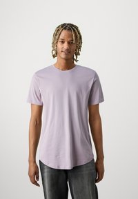 Lavendel crew-neck t-shirt met korte mouwen. Zachte katoenstof, lichtgebogen zoom, gedragen met donkergrijze jeans. Eenvoudig en casual ontwerp.