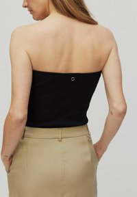 Zwarte geribbelde strapless top met een rechte halslijn en een klein zilveren ringdetail aan de achterkant, gecombineerd met een beige tailleband.