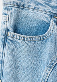Gros plan d'une poche de jean en denim bleu clair avec des coutures visibles et une texture délavée.
