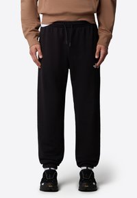 Svarta sweatpants med dragsko i midjan, ribbad mudd och en liten vit logotyp. Tillverkade av mjukt tyg, med en avslappnad passform och sidfickor.