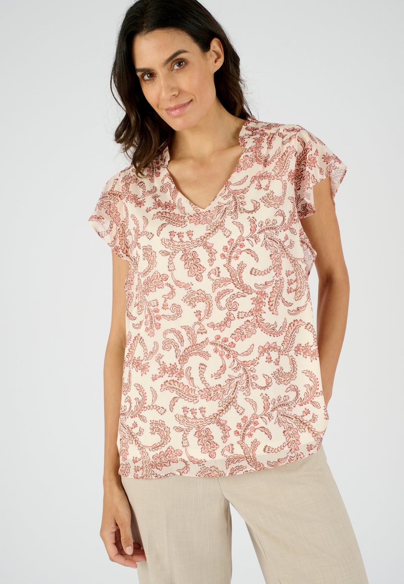 Blouse à motifs floraux dans un rose poudré avec des accents rouges. Dotée d'un encolure en V et de manches courtes volantées, fabriquée en tissu léger.