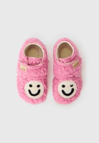 Rosa filttofflor med runda, vita smiley face-applikationer. Mjuk textur, att glida på design och en liten tagg på sidan.