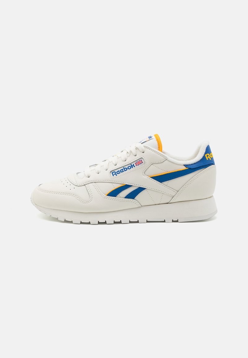 Białe skórzane sneakersy z niebieskimi i żółtymi akcentami, z logo Reebok. Okrągły przód, płaskie sznurowadła i teksturowana gumowa podeszwa.