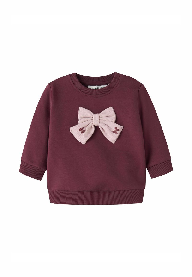 Felpa color bordeaux con un fiocco in tessuto rosa sul davanti. Maniche lunghe, polsini e orlo a costine, texture morbida e dettagli ricamati.