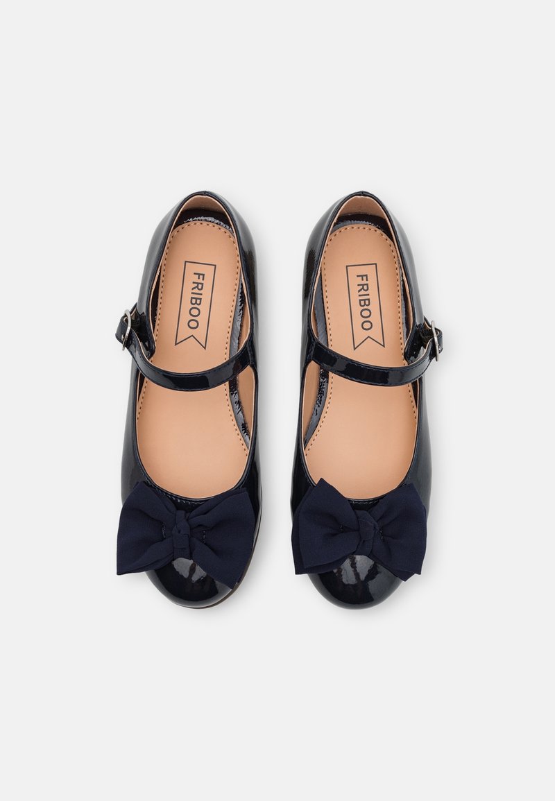 Para czarnych lakierowanych butów Mary Jane z granatowymi materiałowymi kokardkami i paskami na kostkach, beżowymi wkładkami oraz metką marki wewnątrz.