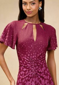 Rochie bordo cu mâneci flutură, decolteu tip cheie și detaliu strâns la talie, având un model discret cu pete.