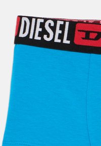 Μπλε ανδρικά μποξεράκια με παχιά μαύρη ζώνη μέσης που φέρει λευκή και κόκκινη επιγραφή "DIESEL". Λείο, ελαστικό ύφασμα.