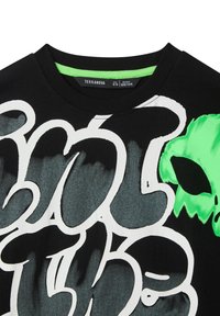 T-shirt in cotone nero con grande testo in stile graffiti bianco e grafica di un alieno verde. Collo a giro con dettaglio interno verde a contrasto.