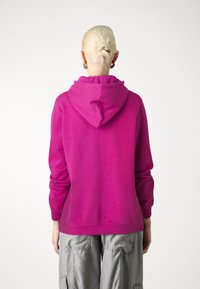 Felpa fucsia con cappuccio regolabile, maniche lunghe e vestibilità morbida. Tessuto liscio con un colore uniforme, senza motivi o accenti visibili.