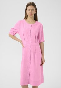 Vestito in lino rosa con scollatura tonda, maniche corte arrotolate, bottoni frontali e vita aderente, che arriva fino al ginocchio.