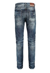 Jean en denim bleu avec un lavage délavé, design à cinq poches et une étiquette en cuir à l'arrière de la taille. Jambe légèrement fuselée.