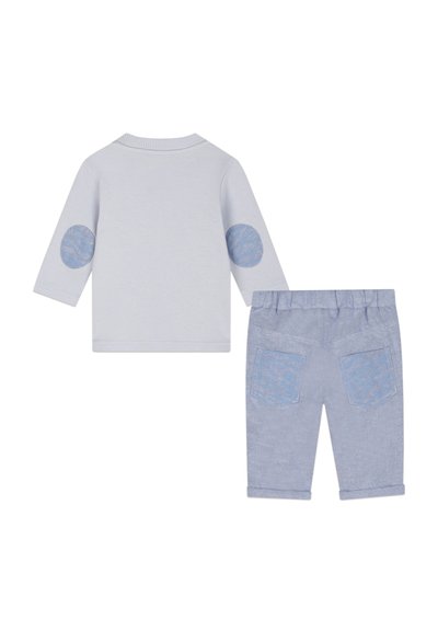 Chemise à manches longues gris clair avec des coudières à motifs bleus, associée à un pantalon court bleu clair avec deux poches arrière.