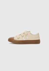 Beige lærstoff sneakers med tre borrelåsremmer, brun gummitåhette og teksturert såle. Hvit stjerne og pil aksent på siden.