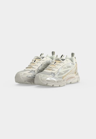 Paire de baskets épaisses crème et beige avec semelles texturées et languettes noires sur fond blanc.