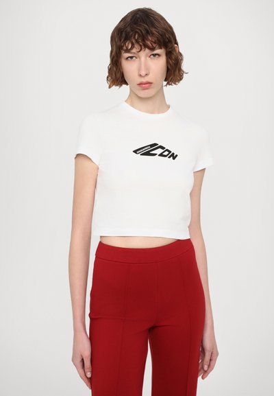 T-shirt blanc court à manches courtes avec un logo noir sur le devant. Associé à un pantalon rouge taille haute.