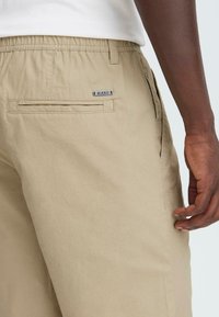 Beige, letvægts bomuldsshorts med elastisk talje, sidelommer og en baglomme med en "BLEND" label. Glat tekstur.