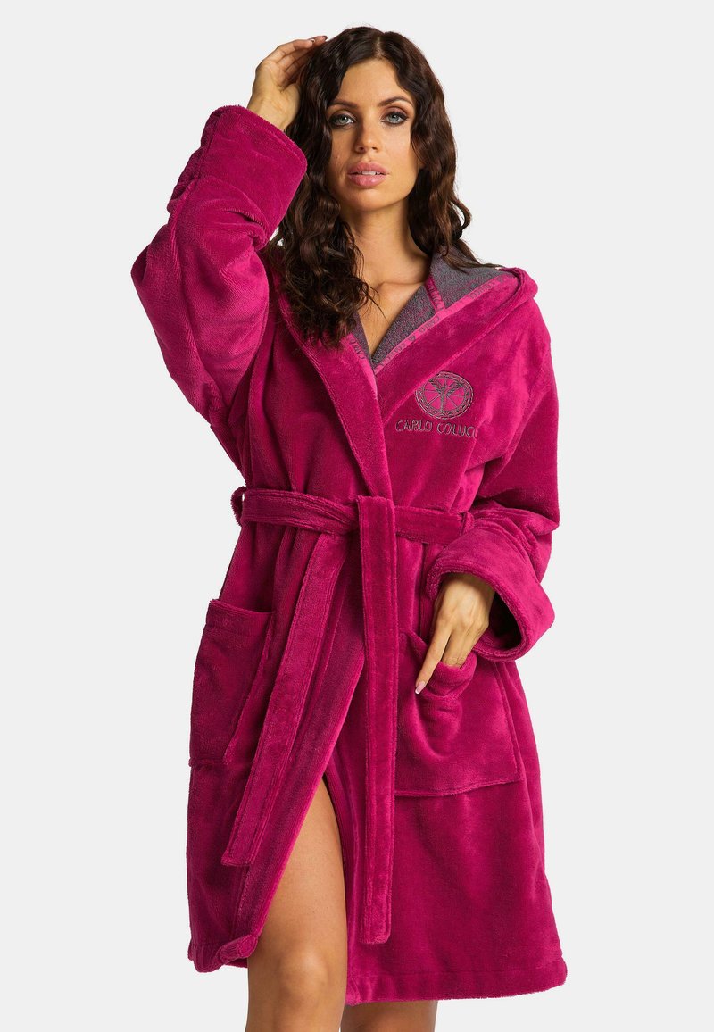 Fuchsia pluche badjas met een capuchon, voorzakken en een ceintuur. Geborduurd logo detail bij de borst voegt een onderscheidende touch toe.
