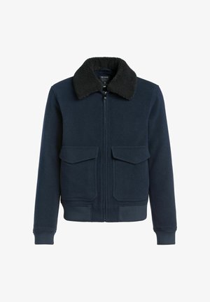 Granatowa kurtka bombowca z czarnym kołnierzem z sherpy, z suwakiem z przodu, dwoma dużymi kieszeniami z klapami oraz ściągaczami na mankietach i u dołu.