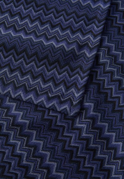 Tessuto intrecciato in tonalità di blu e nero con un motivo a zigzag, caratterizzato da una superficie texturizzata e leggere variazioni di colore.