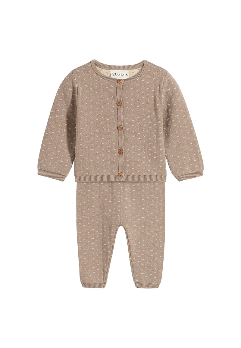 Set di cardigan e pantaloni per neonati in morbido knit beige, con piccoli cuori bianchi e bottoni marroni lungo la parte frontale del cardigan.