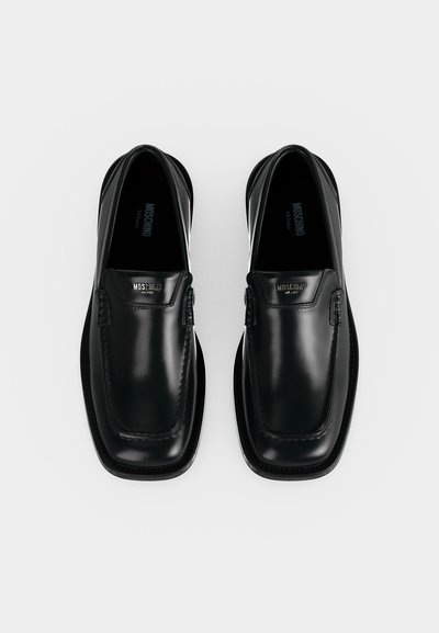 Ζευγάρι μαύρα γυαλιστερά δερμάτινα loafers με τετράγωνες μύτες και τη σήμανση Moschino Milano στο μπροστινό πάνω μέρος.