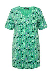 Vihreä lyhythihainen paita, jossa on V-pääntie, musta, violetti ja vaaleanvihreä geometrinen kuosi teksturoituneella kankaalla.